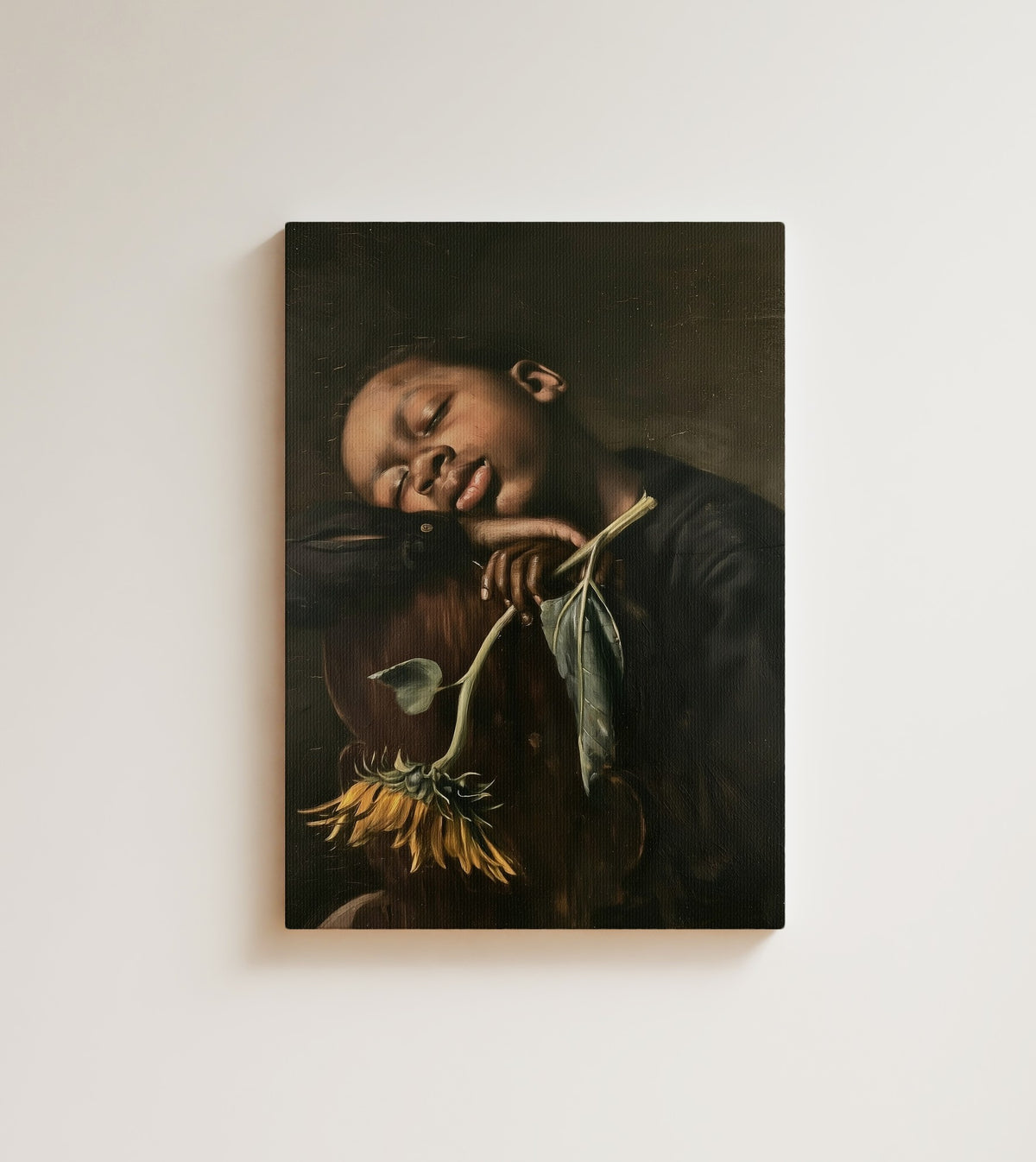 Sleeping Boy with Sunflower: A Black child sleeps on his folded arms, a sunflower in his hand. Canvas wall art, shown on a plain wall