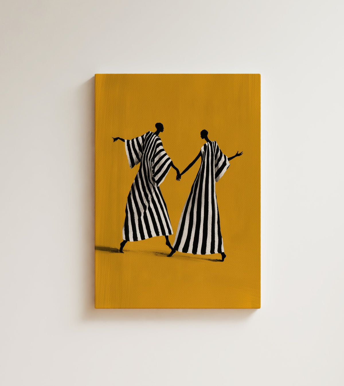 Midday Dance: two tall figures in black and white striped robes go hand in hand across a mustard yellow ground. Canvas wall art, shown on a plain wall