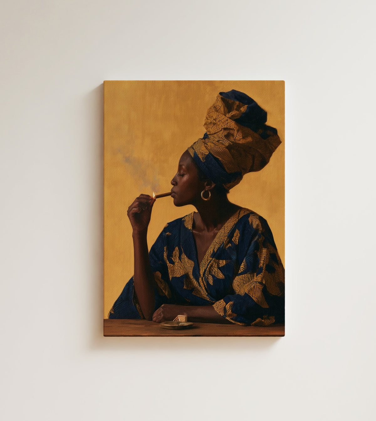 Woman with a Match: A woman in profile against warm gold, her head wrapped in navy and ochre ankara cloth. Canvas wall art, shown on a plain wall