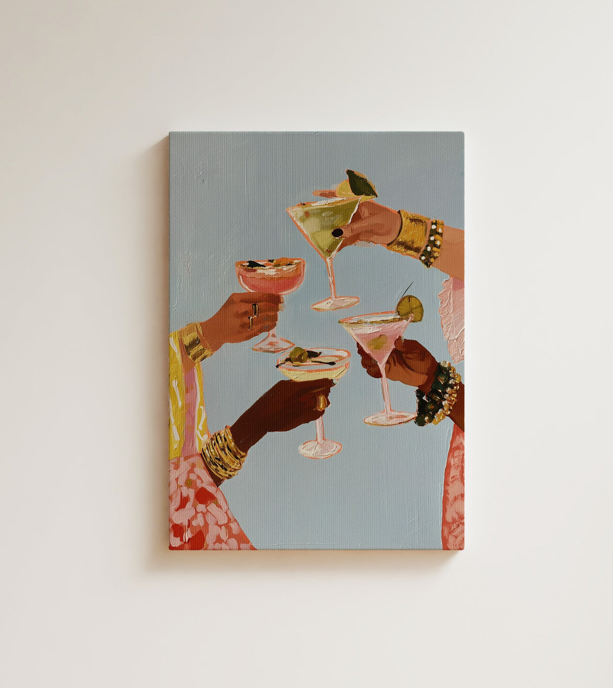 A Toast at Five: four Black women raise cocktails against dusty blue, gold bangles at every wrist. Canvas wall art, shown on a plain wall
