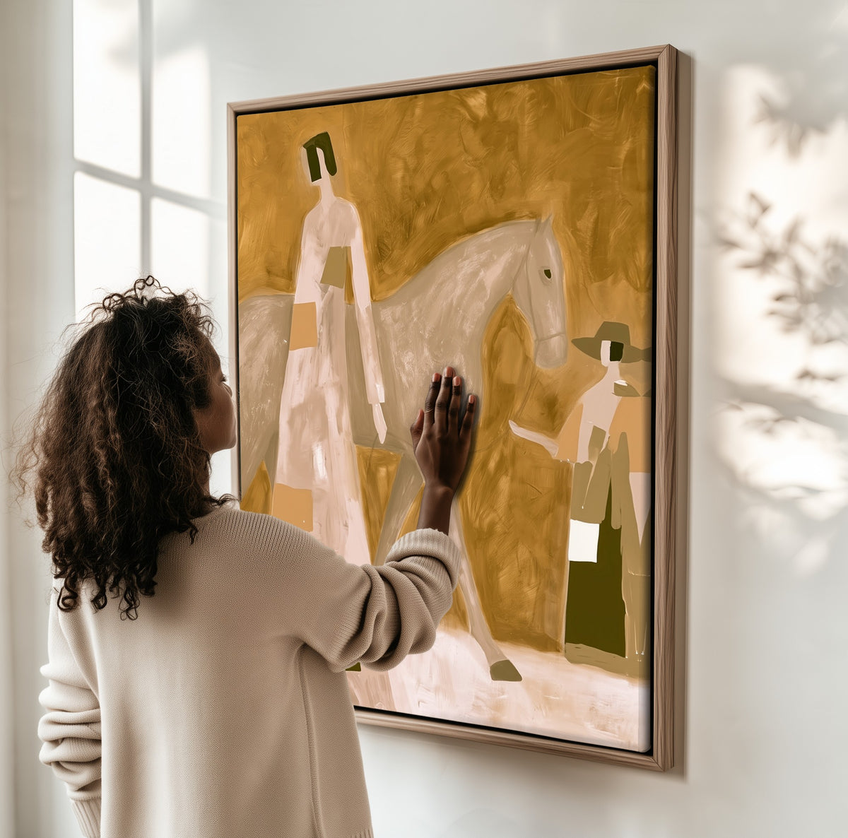 Ochre Distance framed canvas, a woman hanging it on a sunlit wall