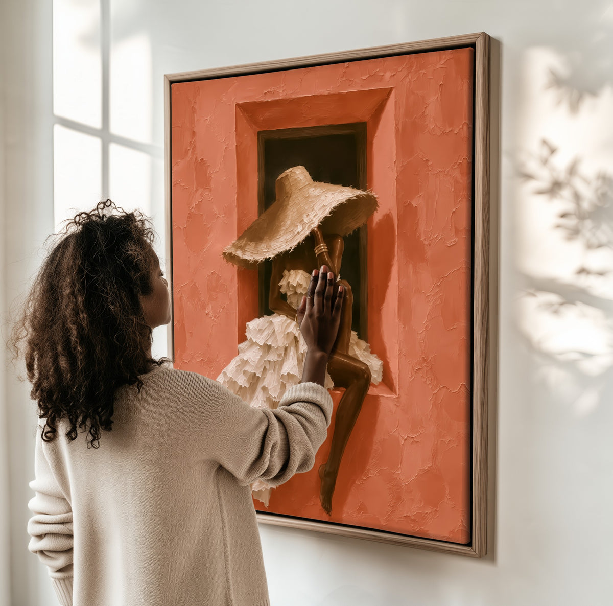 The Window Seat framed canvas, a woman hanging it on a sunlit wall