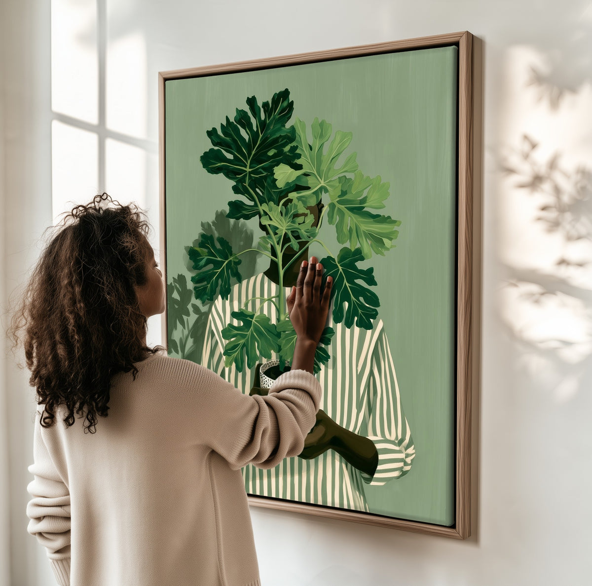 Quiet Growth framed canvas, a woman hanging it on a sunlit wall