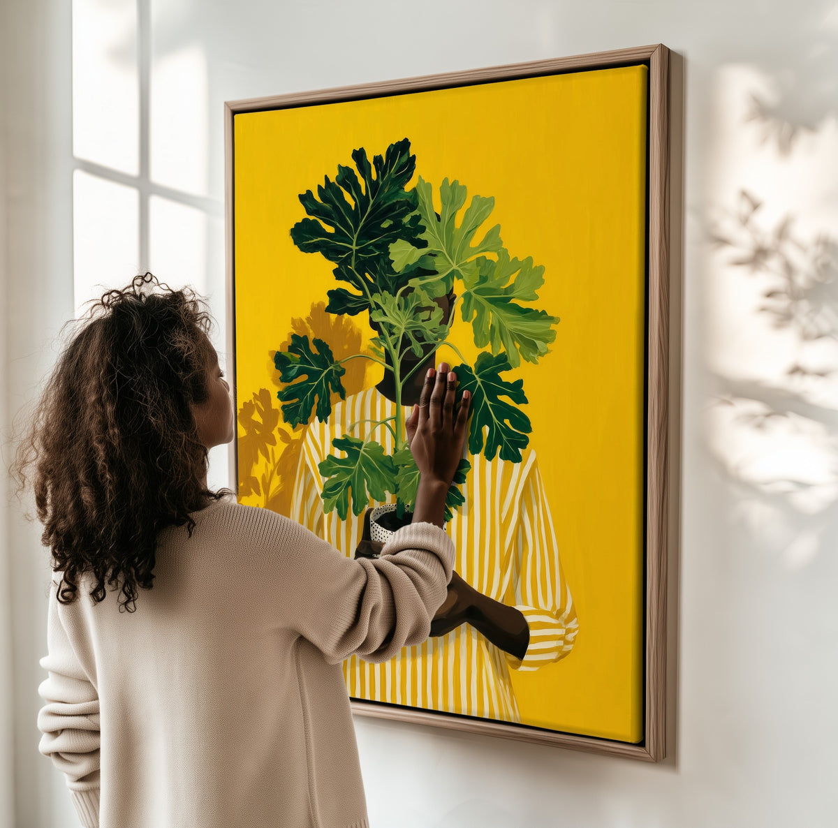 Leaf and Light framed canvas, a woman hanging it on a sunlit wall