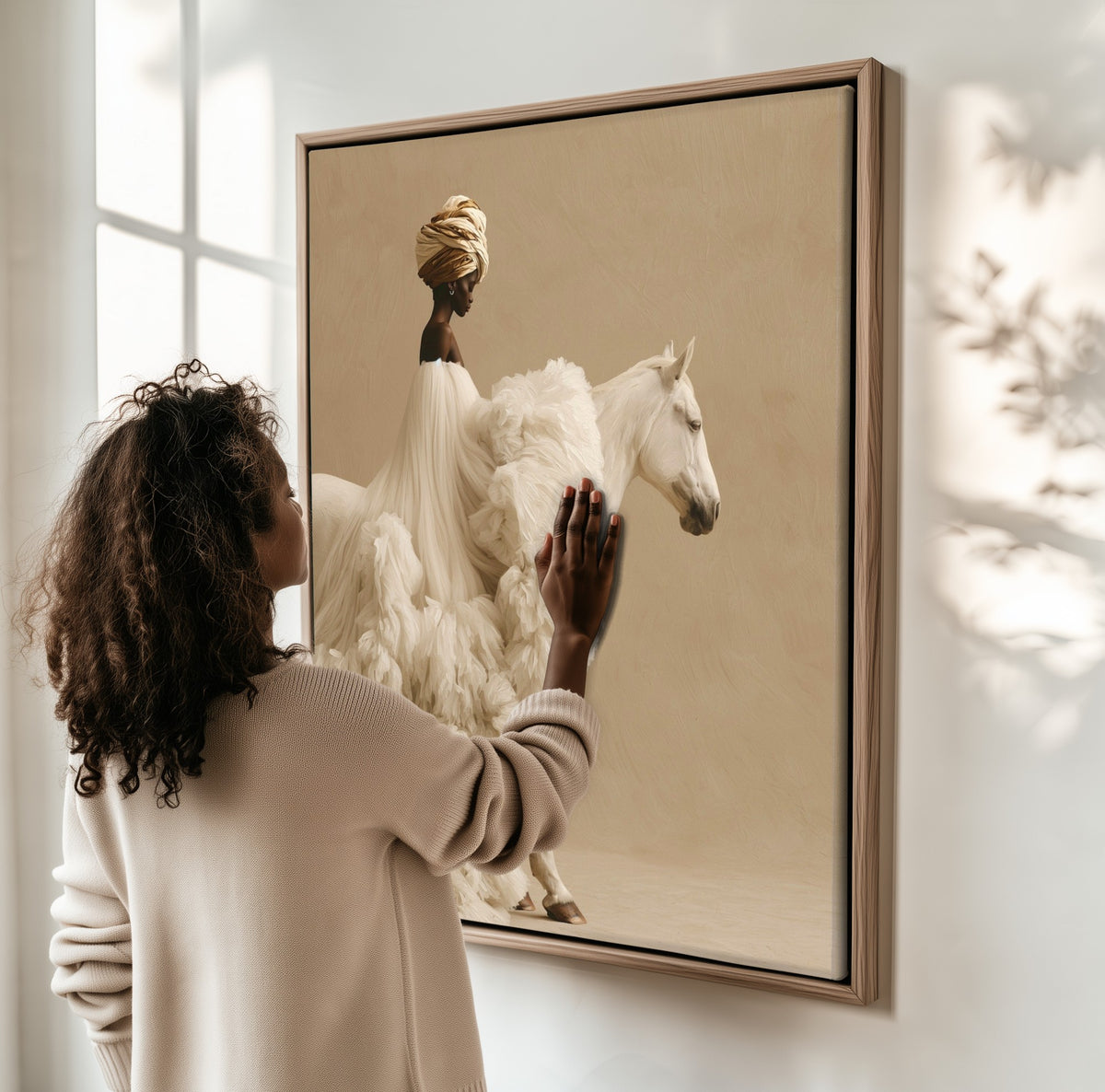 The White Mare framed canvas, a woman hanging it on a sunlit wall