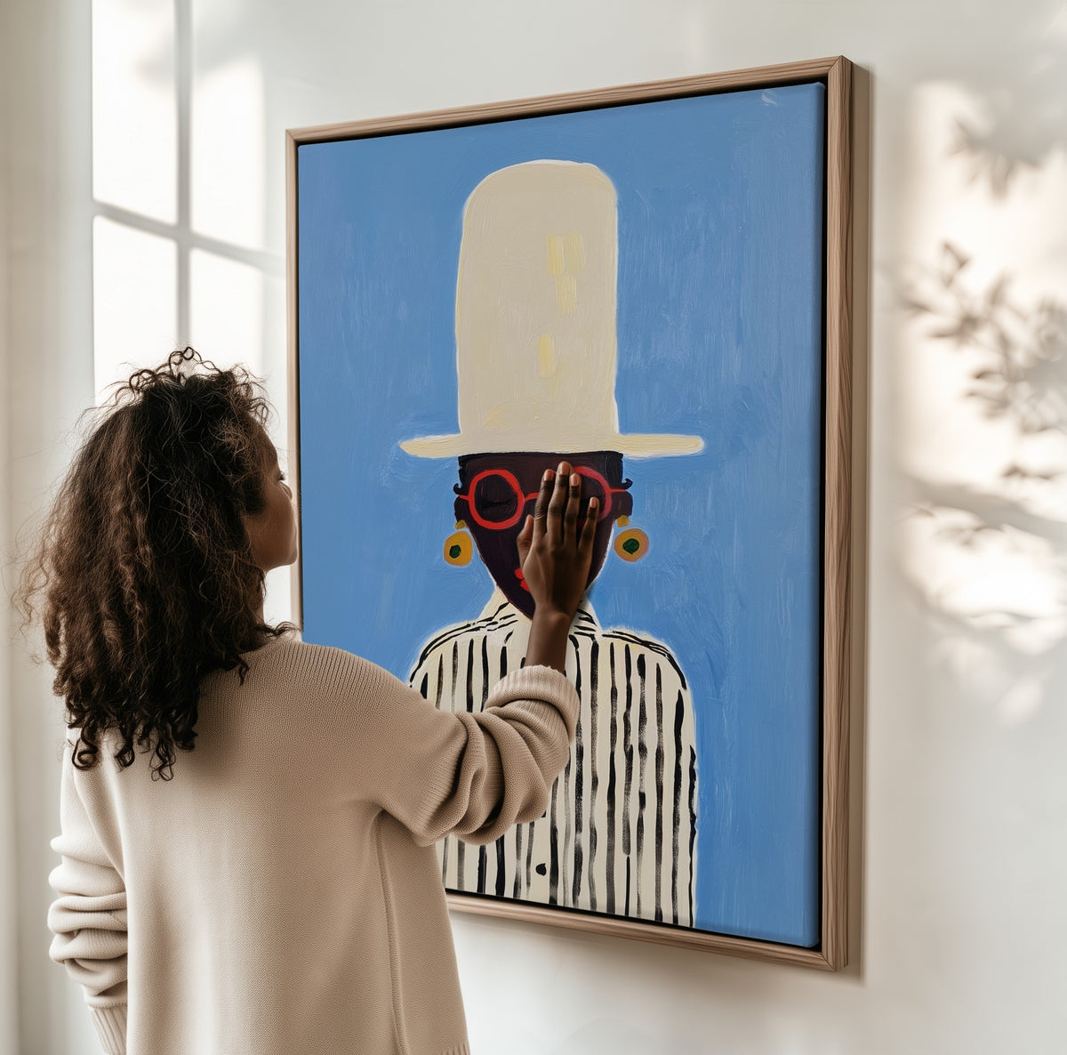 Elevation framed canvas, a woman hanging it on a sunlit wall