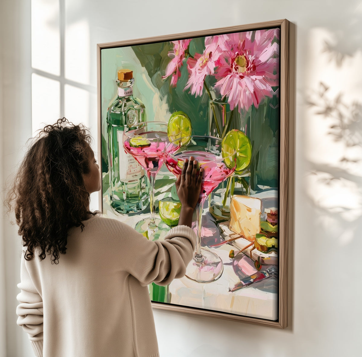 Still Life with Cosmopolitans framed canvas, a woman hanging it on a sunlit wall